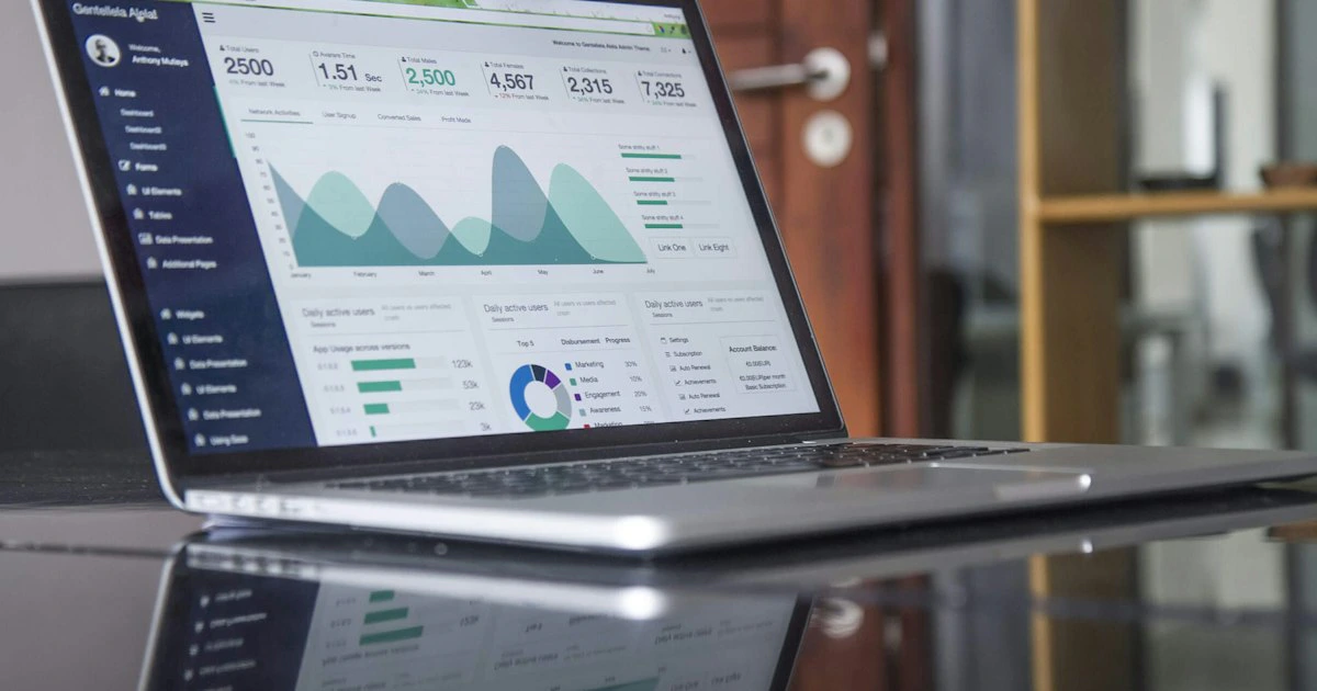Laptop showing data analytics graphs on a reflective desk